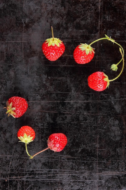 Red juicy sweet strawberries with twigs on a black background Closeup of red berries Healthy food concept