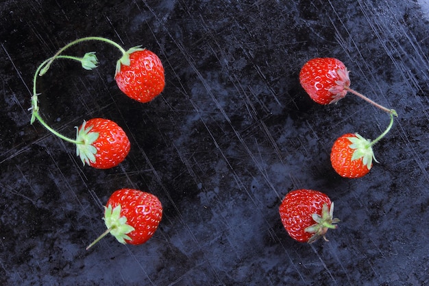 Red juicy sweet strawberries with twigs on a black background Closeup of red berries Healthy food concept