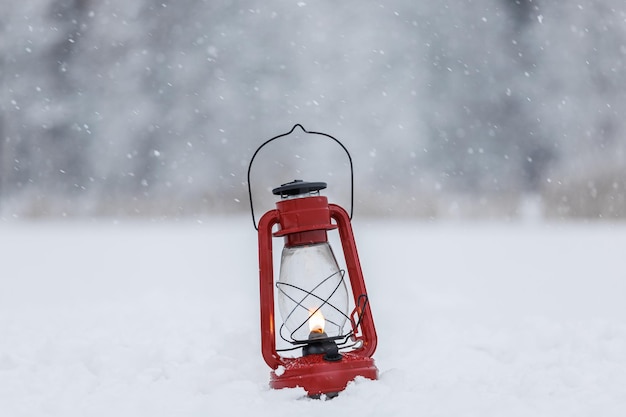 A red kerosene lamp burns in the forest on the snow