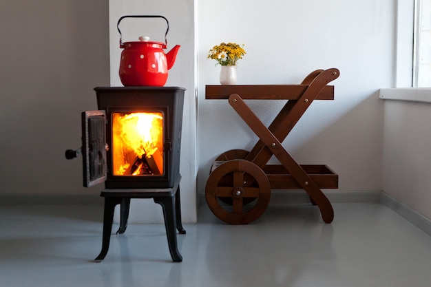 red kettle boiling on a retro stove in the kitchen country home design with furnace at the interior