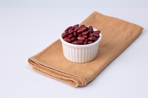 Red kidney bean in white bowl on cloth and white background studio shot