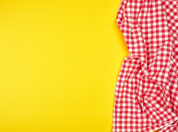 Red kitchen towel in a cage on a yellow background