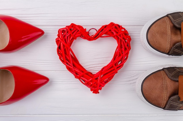 Red knitted heart and footwear on white desk