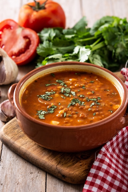 Red lentil soup in bowl on rustic wooden table