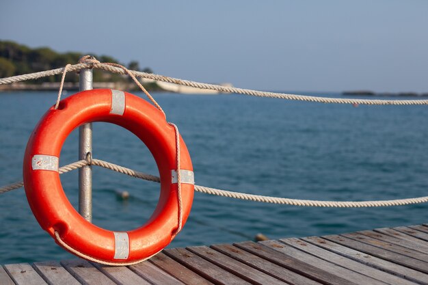 Red life buoy near the fence on a wooden pier. bright sunny weather