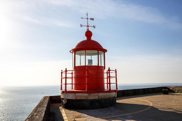 Red lighthouse lamp room on blue sky and sea background