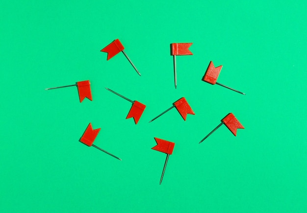 Red little flag pins on a green background. View from above .