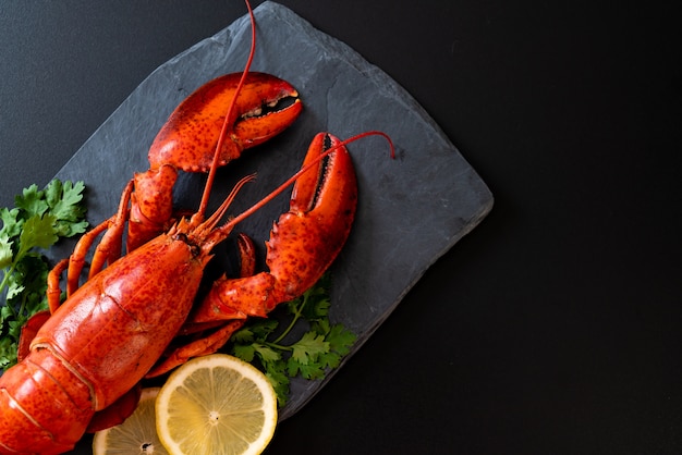 Red lobster with vegetable and lemon slices on black slate