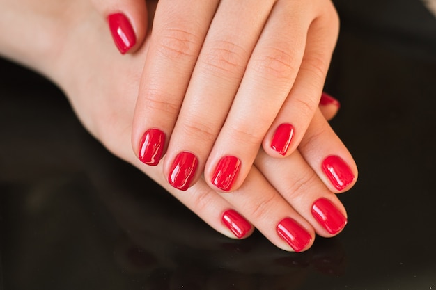 Red manicure with nail on a black surface