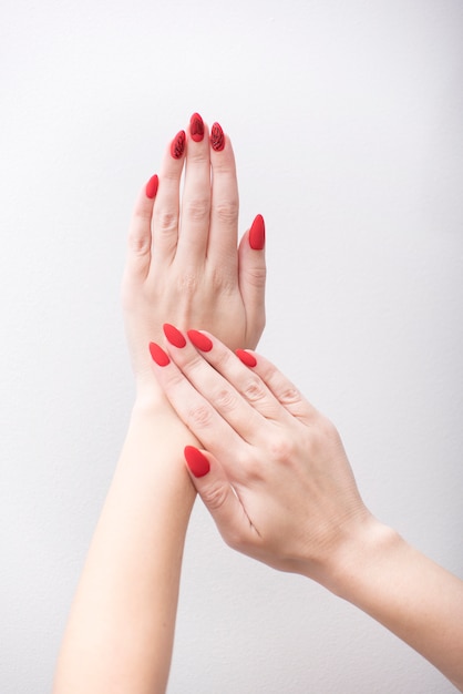 Red manicure with a pattern. Female hands on a white background