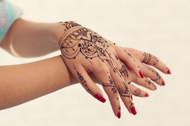 Red manicured hands with Mehndi