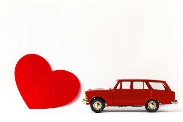 Red metal retro toy car and heart on white background Valentines day concept