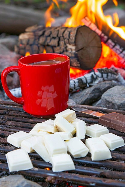 a red mug of coffee sits next to a fire with the words  coffee  on it