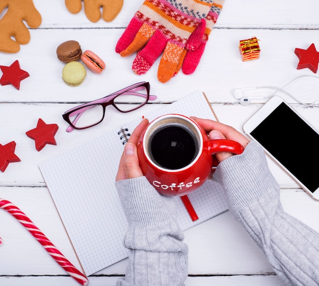 Photo red mug with black coffee in female hands over a table