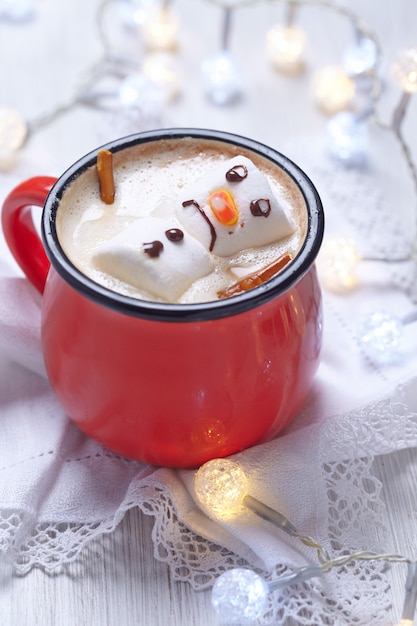 Red mug with hot chocolate with melted marshmallow snowman