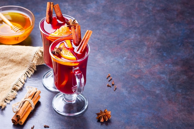 Red mulled wine on burlap Mulled wine with oranges cinnamon and cloves on dark background