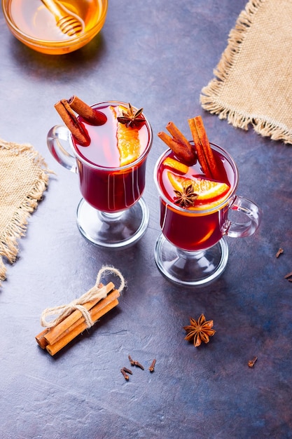 Red mulled wine on burlap Mulled wine with oranges cinnamon and cloves on dark background