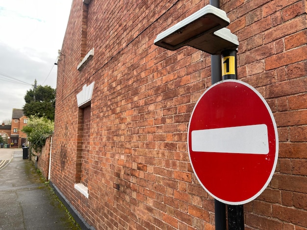 Red no entry for vehicular traffic sign near brick wall in old town