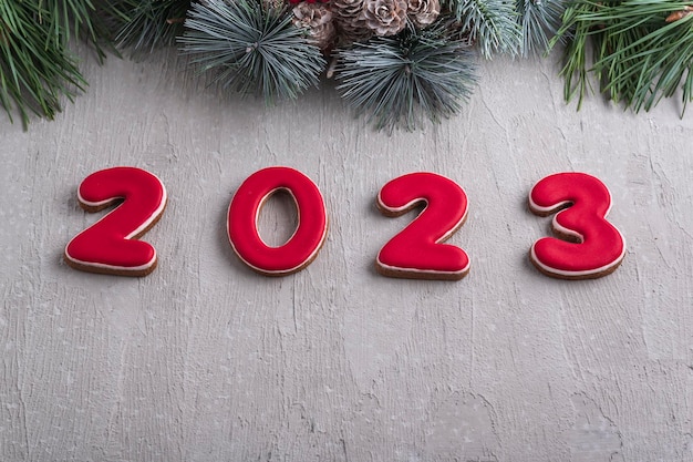 Red number 2023 from gingerbread and christmas wreath Good New Year spirit Light gray wall on background