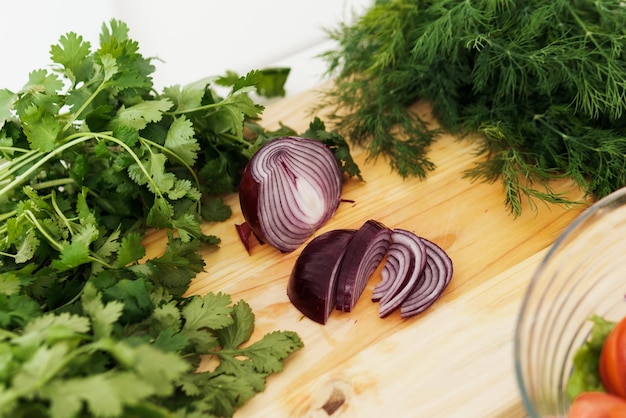 Red onion and green herbs on wooden cutting board