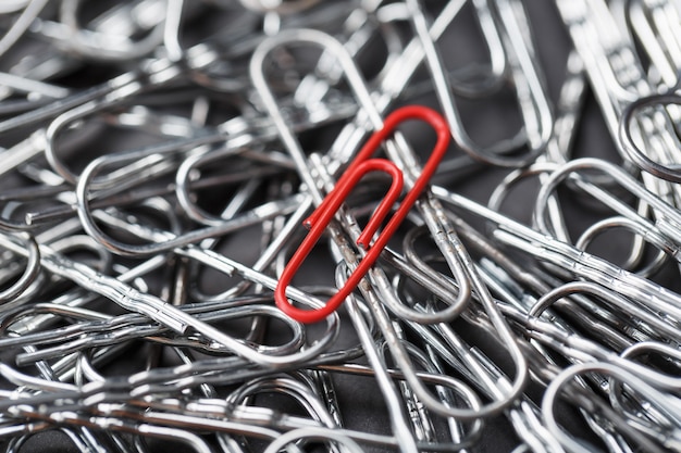 Photo a red paper clip stands out against a textured background of silver paper clips