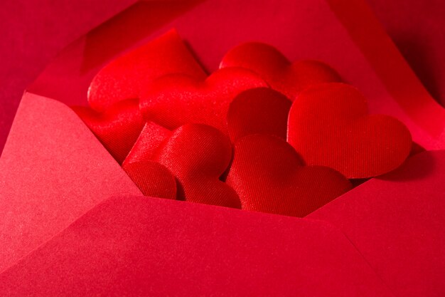 Red paper envelope with hearts inside isolated on red surface Valentine's Day concept close up