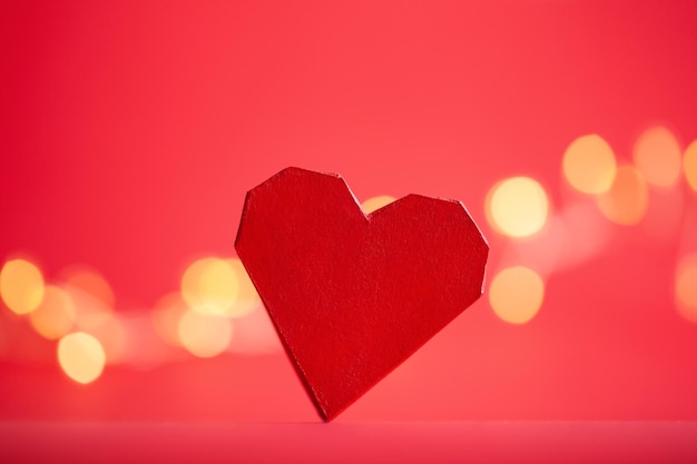 Red paper handmade heart on red background with festive boke Creative greeting card for Saint Valentine day