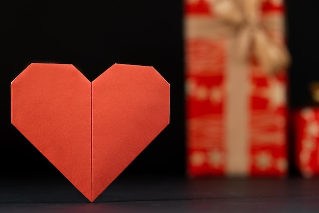 Red paper heart and gifts on a black background