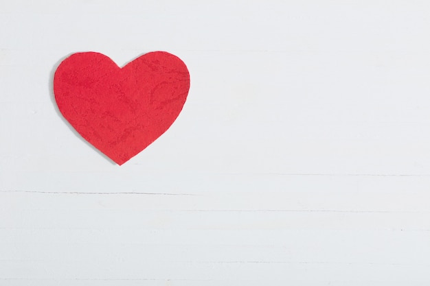 Red paper heart on white wooden background