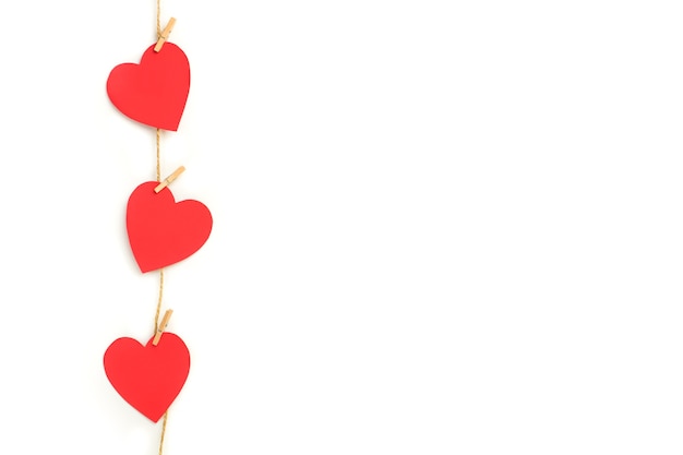 Red paper hearts hanging by a sisal yarn on a white background