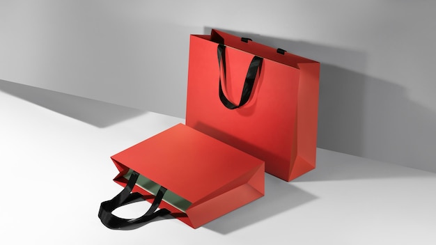 Red paper shopping bags mockup with black handles on grey background