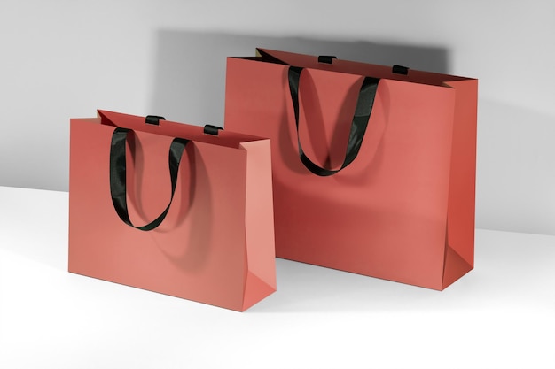 Red paper shopping bags mockup with black handles on grey background