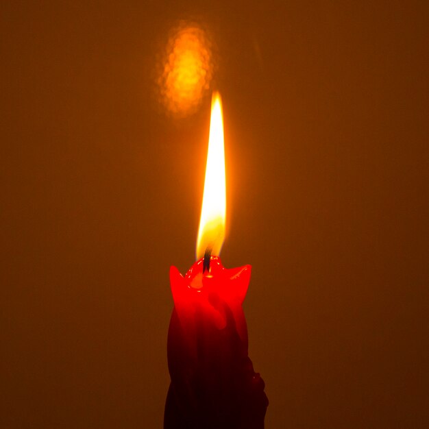 Red paraffin mournful commemorative thick candle burns on a black background close-up