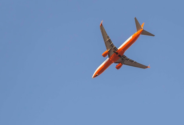 red passenger plane close-up flying in the sky