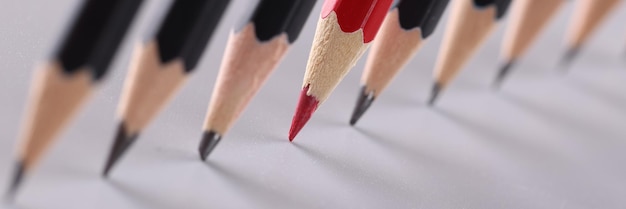 Red pencil separating row of black pencils