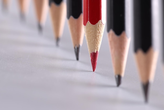 Red pencil stands out from crowd of many identical black pencils