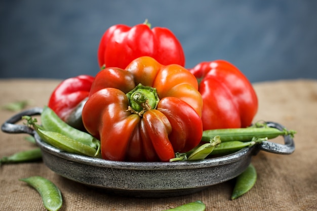 Red pepper in a metal plate with green peas on a table