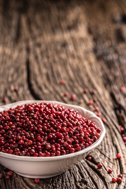 Red peppercorn in bowl on oak table.