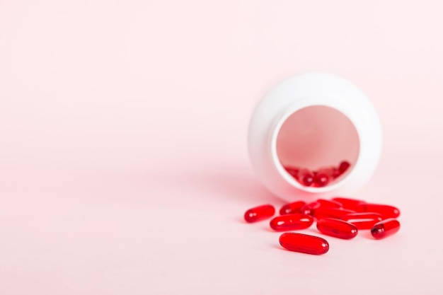 Red pills spilled around a pill bottle Medicines and prescription pills flat lay background Red medical capsules