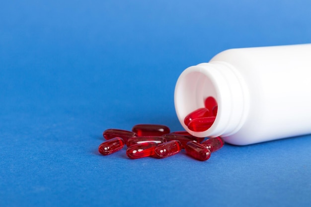 Red pills spilled around a pill bottle Medicines and prescription pills flat lay background Red medical capsules