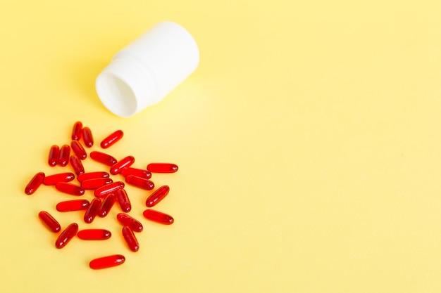 Red pills spilled around a pill bottle Medicines and prescription pills flat lay background Red medical capsules