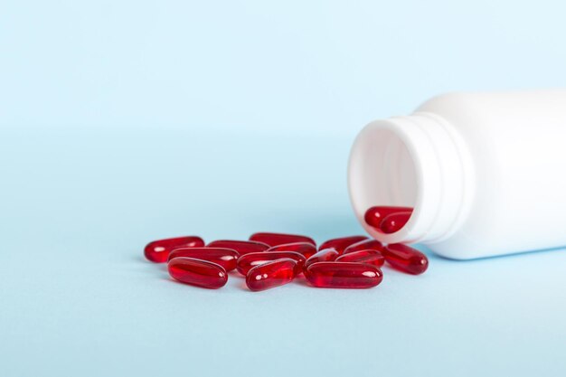 Red pills spilled around a pill bottle Medicines and prescription pills flat lay background Red medical capsules