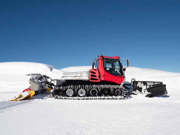 Red piste caterpillar for snow grooming in ski resorts at sunny winter day