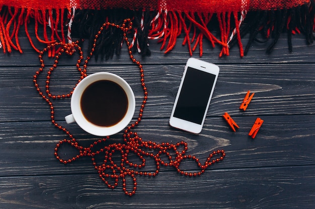 Red plaid, fragrant coffee, silver spoon and smartphone on vintage wooden table.