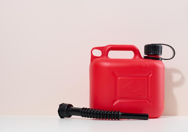 Red plastic canister for liquid fuels and lubricants on a beige background