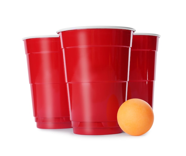 Red plastic cups and ball for beer pong on white background