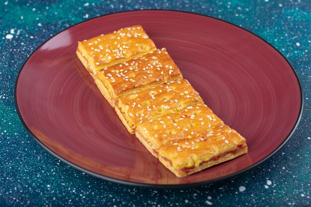 Red plate of sweet crackers with sesame seeds .