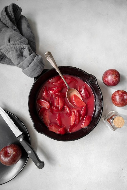 Red plums confiture or jam Cooking fresh fruit sauce in black pan