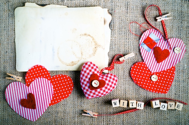 Red polka dot textile hearts on burlap. Free space for your text.