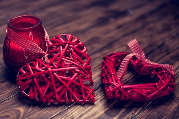 Red rattan heart on wooden table, candle romance background